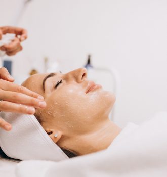 Cosmetologist cleaning face of a woman in a beauty salon
